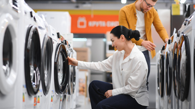 A couple is looking at washing machines in a store