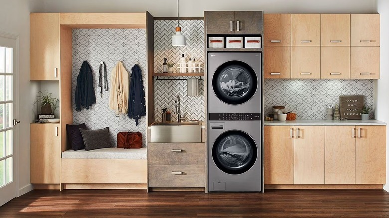 A stacked washer-dryer combo in a narrow laundry area near the entryway