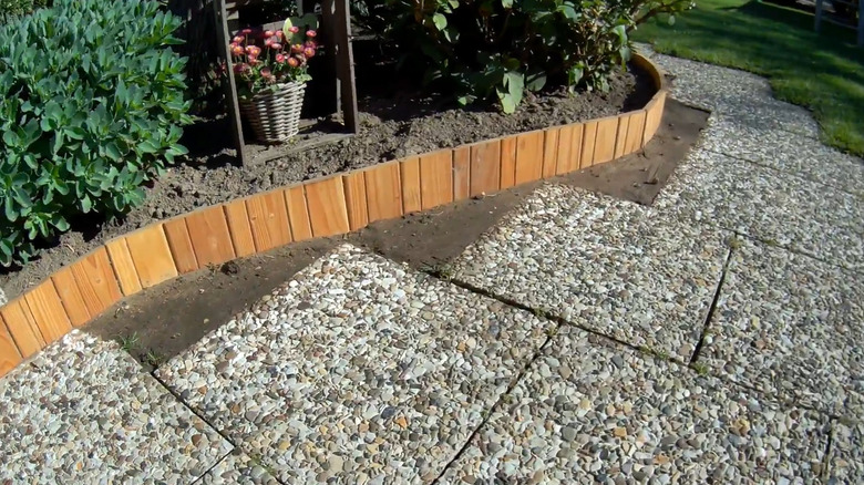 Wood garden edging made with small vertical planks with plants behind it