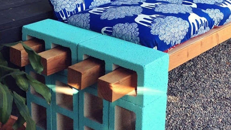 End of a garden bench made from cinder blocks with wood going through the holes