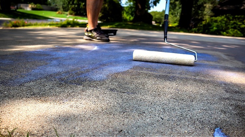A person applying sealant to a concrete driveway