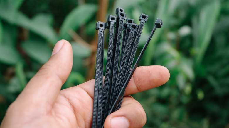 Hand holding black cable ties