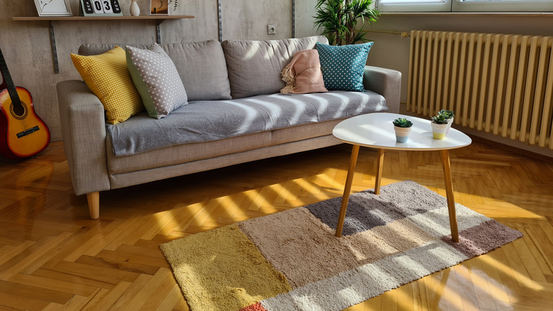 A modern living room with a wool rug, cloth-covered sofa, and a small coffee table