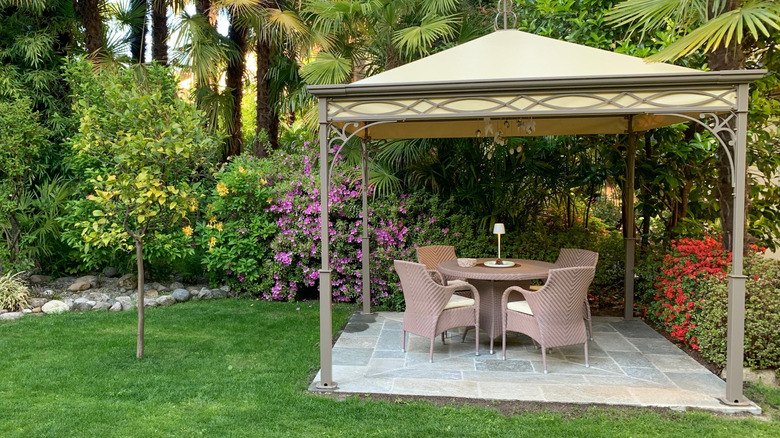 A table for four set under a gazebo in a garden