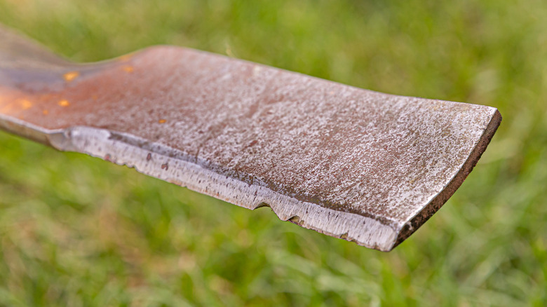Close-up of a dull, chipped mower blade that needs sharpening