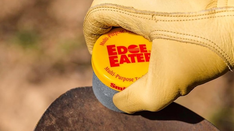 Close up of a hand in yellow leather gloves sharpening a metal tool with the Smith's Edge Eater from Amazon