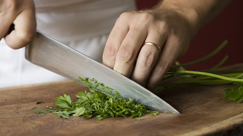 Man chops parsley on cutting board