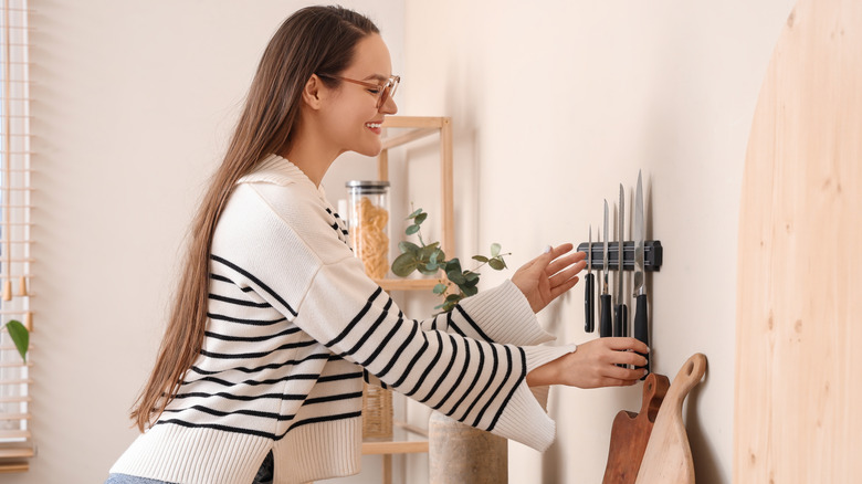 Woman grabbing knife from wall-mounted magnetic knife holder