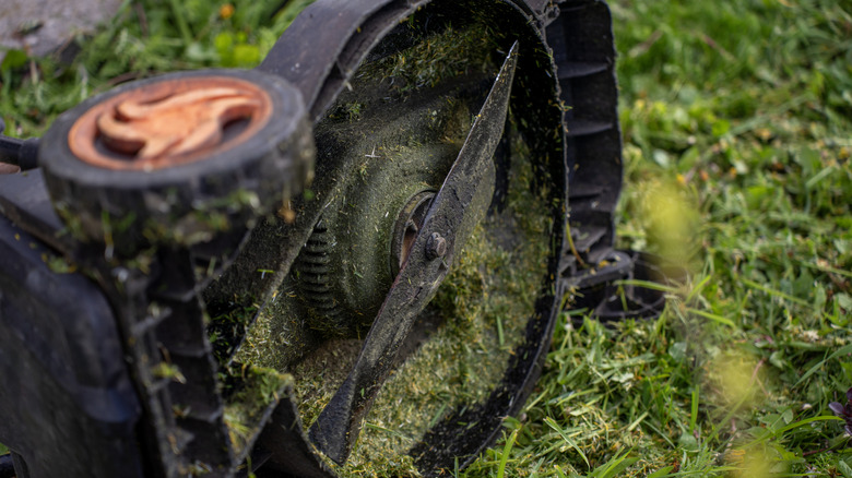 A lawn mower turned on its side, exposing the blade