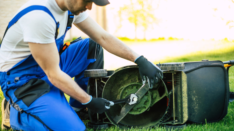 A man removing the blades from a lawn mower