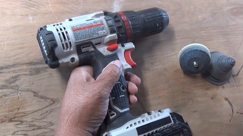 Person attaching a mower blade grinder to a drill