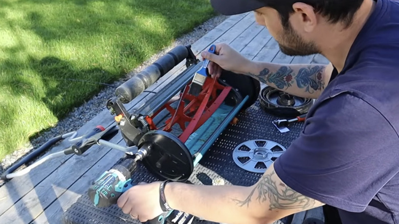 A man using the backlapping technique to sharpen the blades on a reel mower