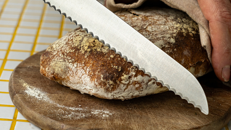 Close-up of a serrated knife about to slice a loaf of bread