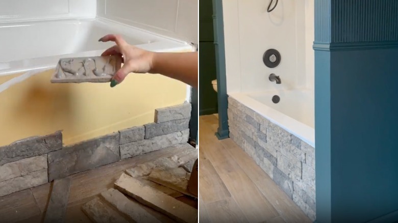 A hand holds a stone veneer brick with glue on it in front of a bathtub and a stone-lined bathtub in a modern, renovated bathroom.
