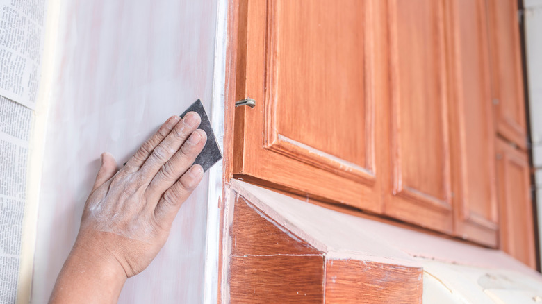 Person sanding side of kitchen cabinet
