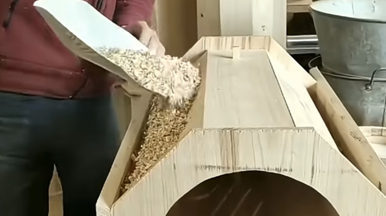 Filling the cavity in the DIY beehive with sawdust