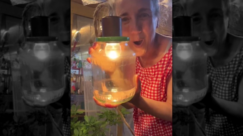 A woman holding a pickle jar porch lamp.