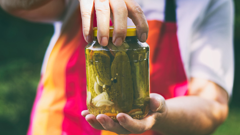 A pair of hands holding a pickle jar.