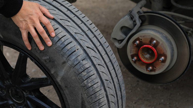 Person holding an old car tire that has been taken off the wheel