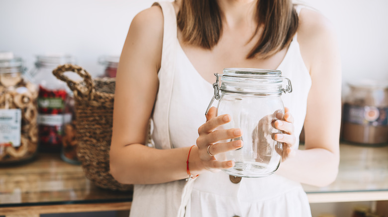 A lady in a white dress holding an empty glass jar