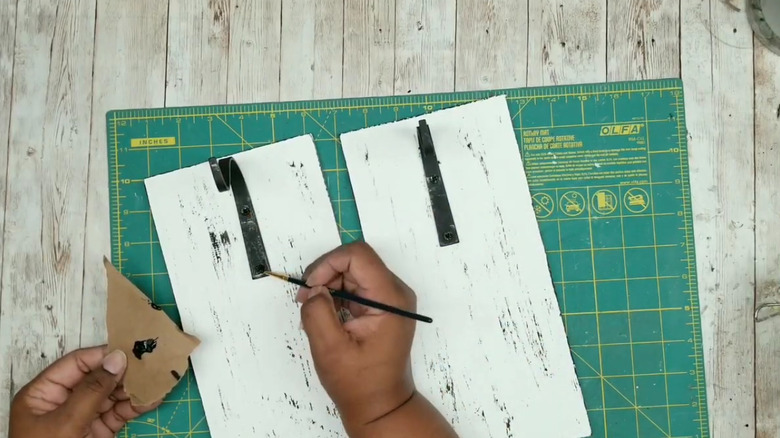 A pair of hands painting a sconce mount
