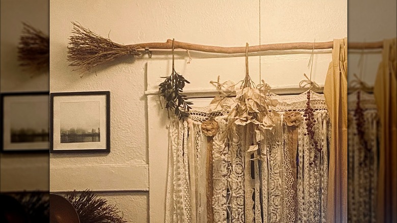 A broomstick curtain rod holds up lace curtains and dried herbs.