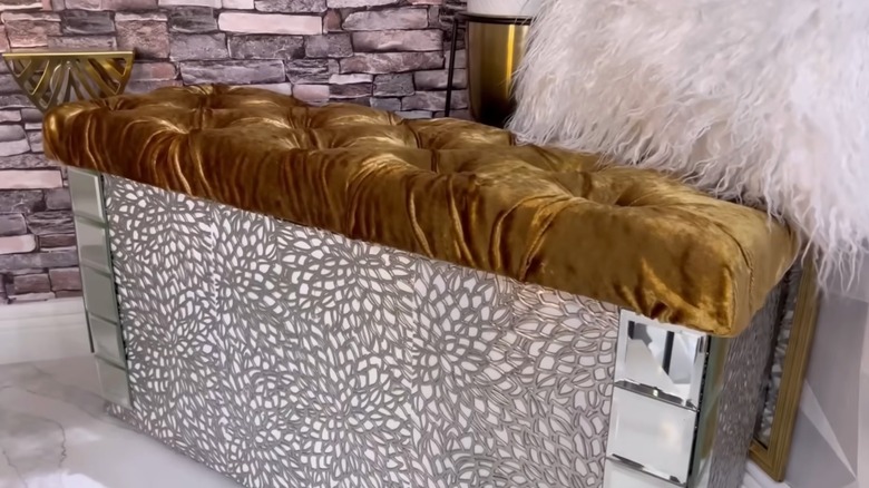 A DIY bedroom bench with gold seat an embellished with placemats and mirrors