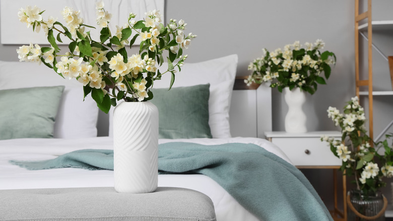 Close up of bedroom with a bedroom bench on the end and a vase of flowers