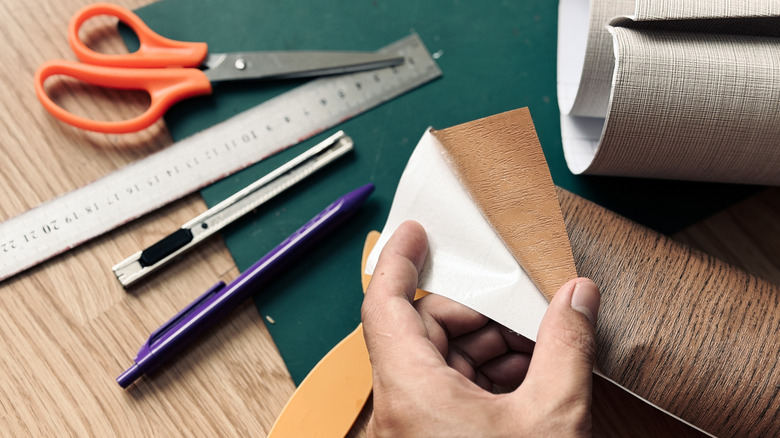 A person doing crafts with window cling on a table filled with art tools.