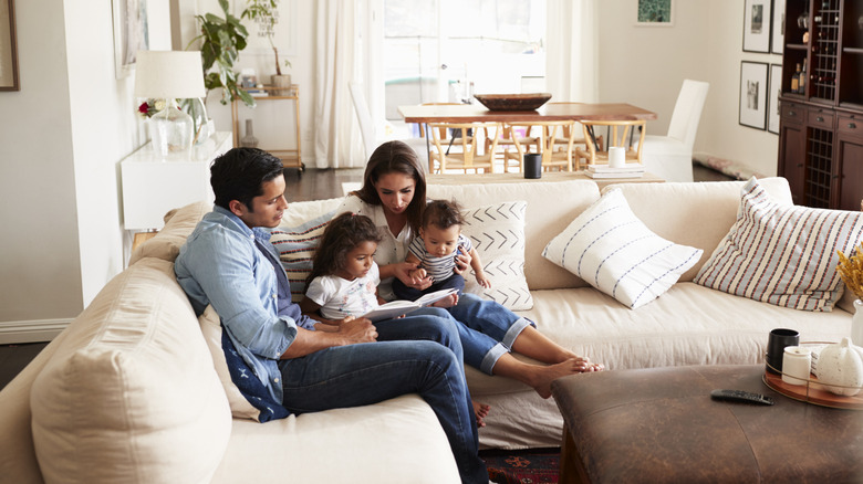 A family is gathered together on the sofa, mother and father reading to their children