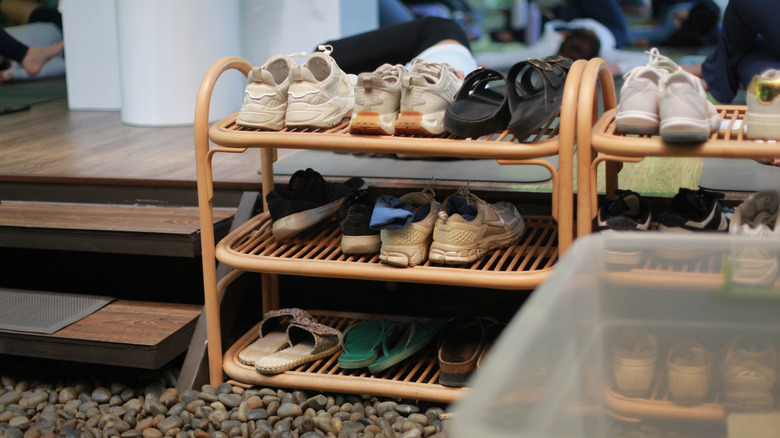 Two rattan shoe racks filled with sneakers and shoes