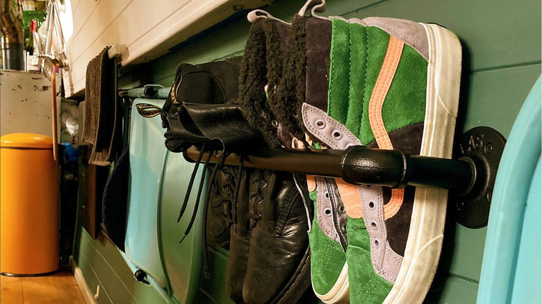 Two towel rails on the wall being used to hold trainers and smart shoes.