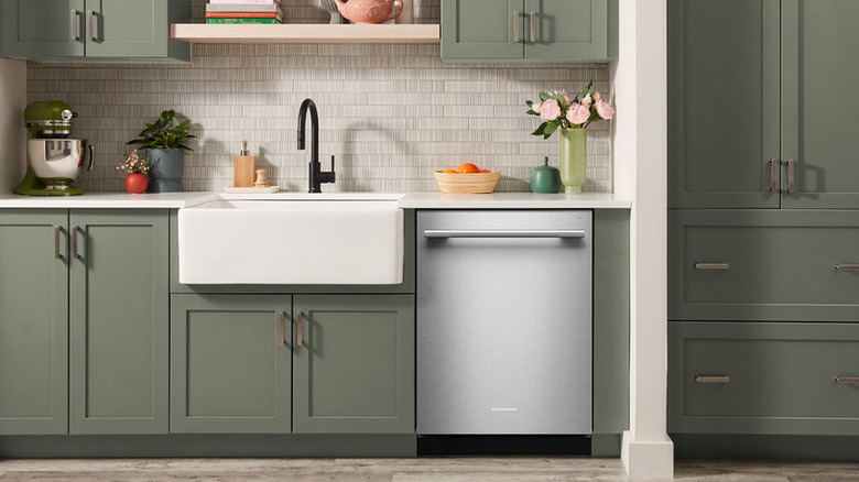 A dishwasher next to a farmhouse sink in a modern kitchen
