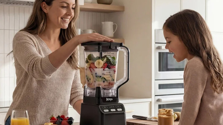 A woman and girl blending up fruits in a blender at a kitchen island