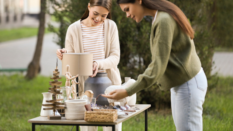 Two women looking over the items on a table at a yard sale