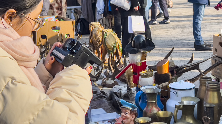 Person inspecting an old camera from a table of random items