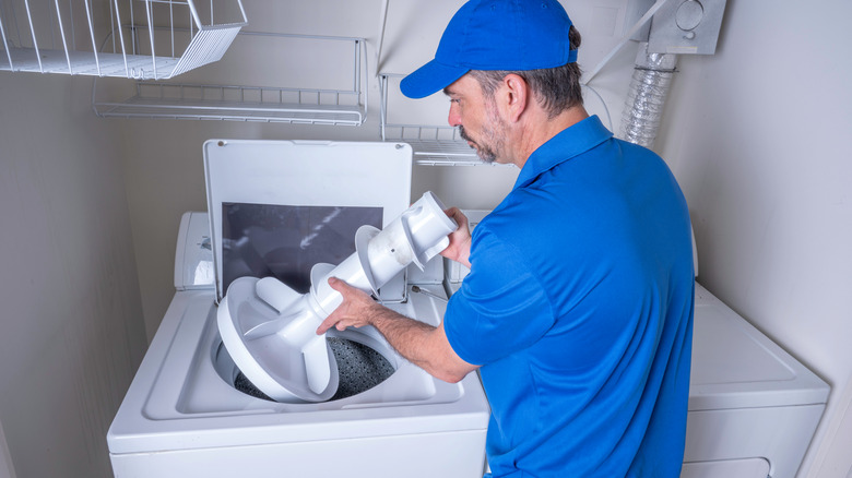 Technician removing agitator from a top load washer