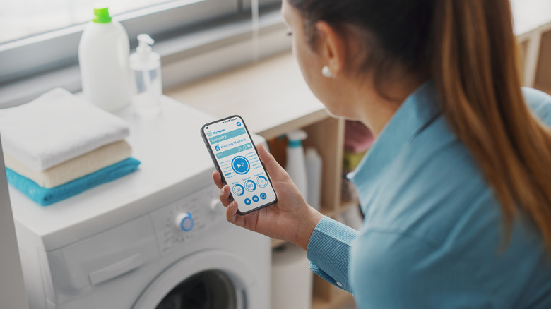 Woman looking at laundry app in front of smart washer