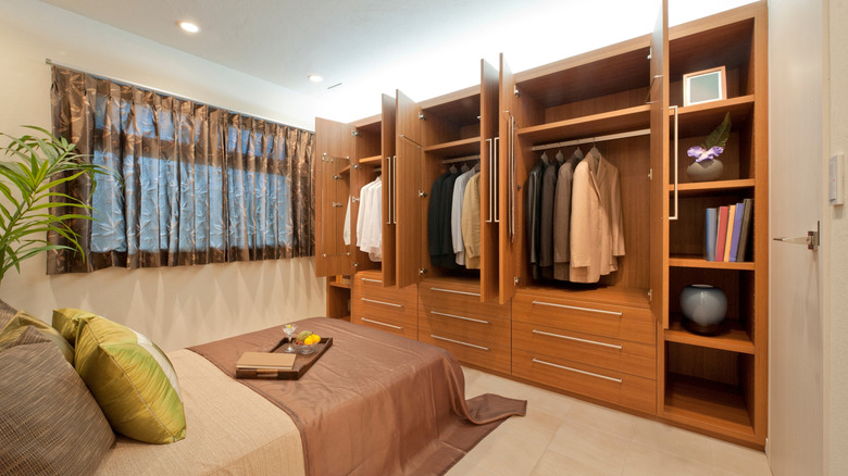 Stylish bedroom with a blank art frame mockup. Features a leather headboard, warm sconce lighting, and built-in wooden shelves.