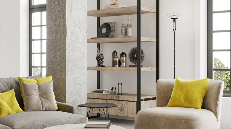 Modern apartment living room interior with an armchair, sofa with pillows, coffee table, shelf, white walls and big windows.