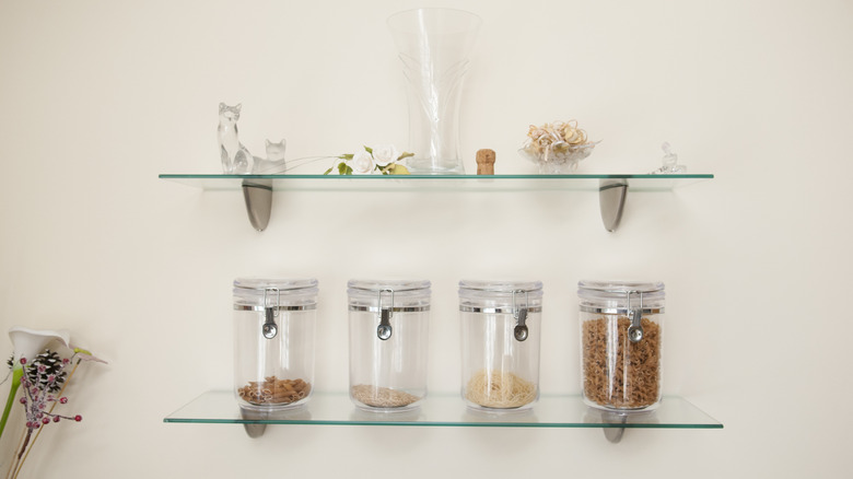 Glass shelves displaying canisters of ingredients and spices in the kitchen.