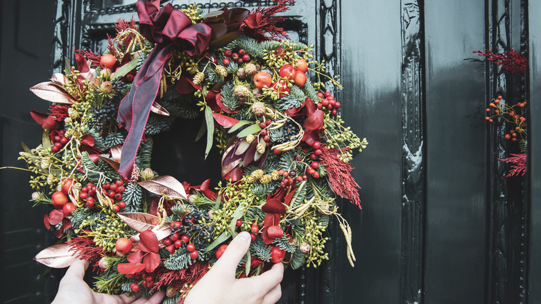 A person hanging a wreath on the front door