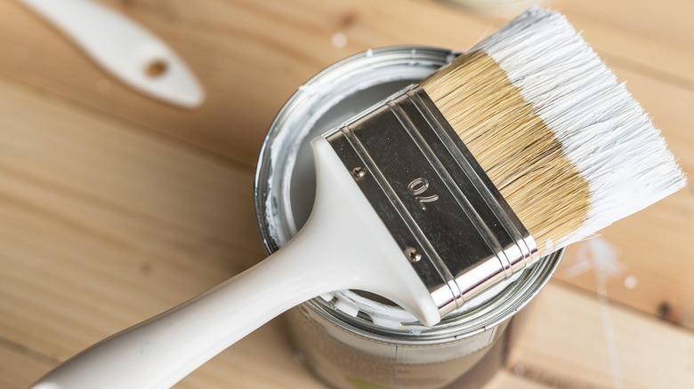 Paintbrush resting on white paint can