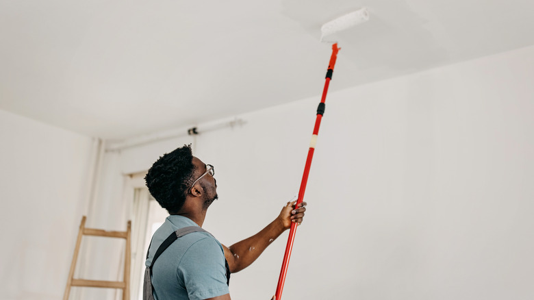 man painting ceiling with roller