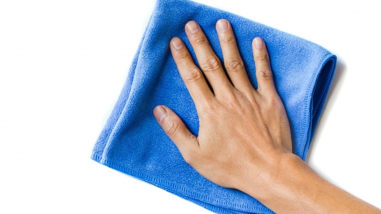 Hand wiping wall with cloth