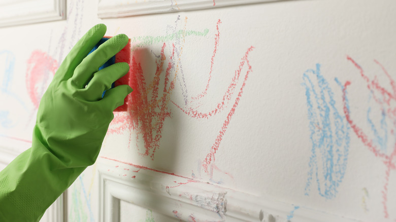 Gloved hand cleaning wall