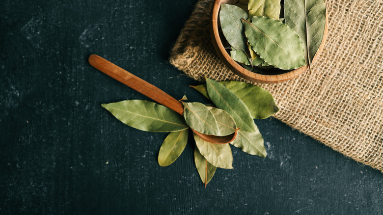 Dried bay leaves in a wooden bowl and a wooden spoon