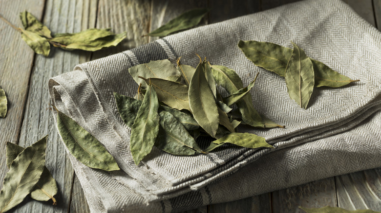 Bay leaves on a white cloth placed on a wooden surface