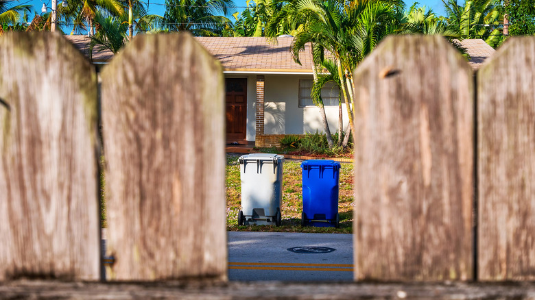 view through the fence of neighbor's trash cans