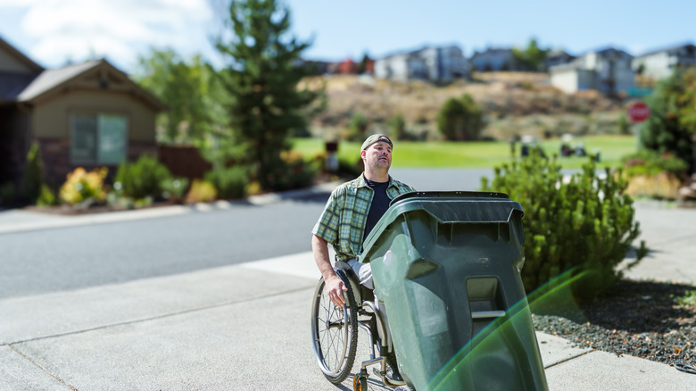 Man in wheelchair bringing garbage bin back from street